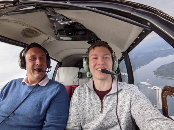 Photograph of Colton and flight instructor sitting in cockpit of small prop plane midflight.